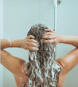 Back view of a woman shampooing her hair in the shower