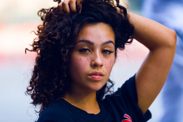 A beautiful mixed-race woman running her hands through her dark curly